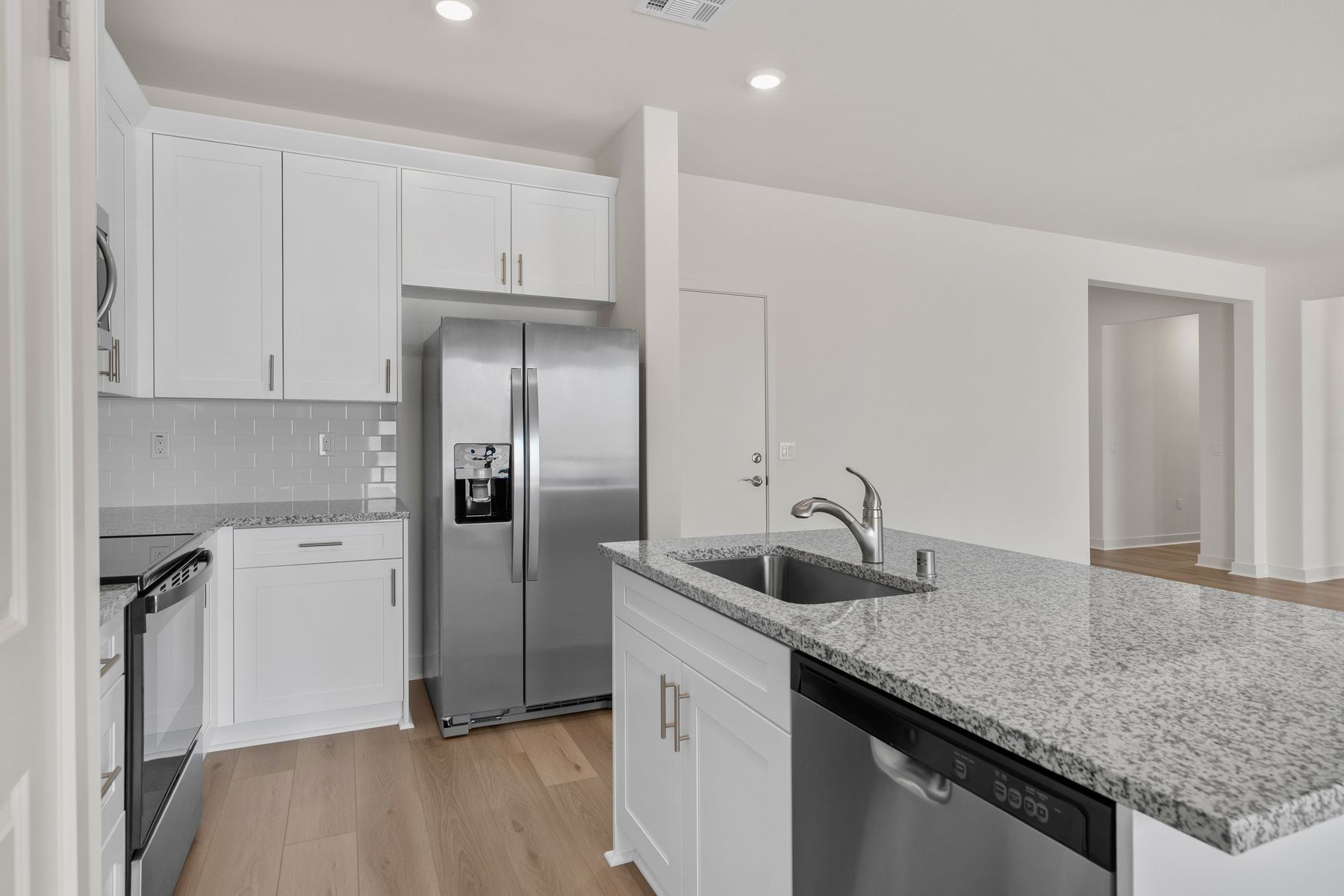 The kitchen has stainless steel appliances and plank flooring.