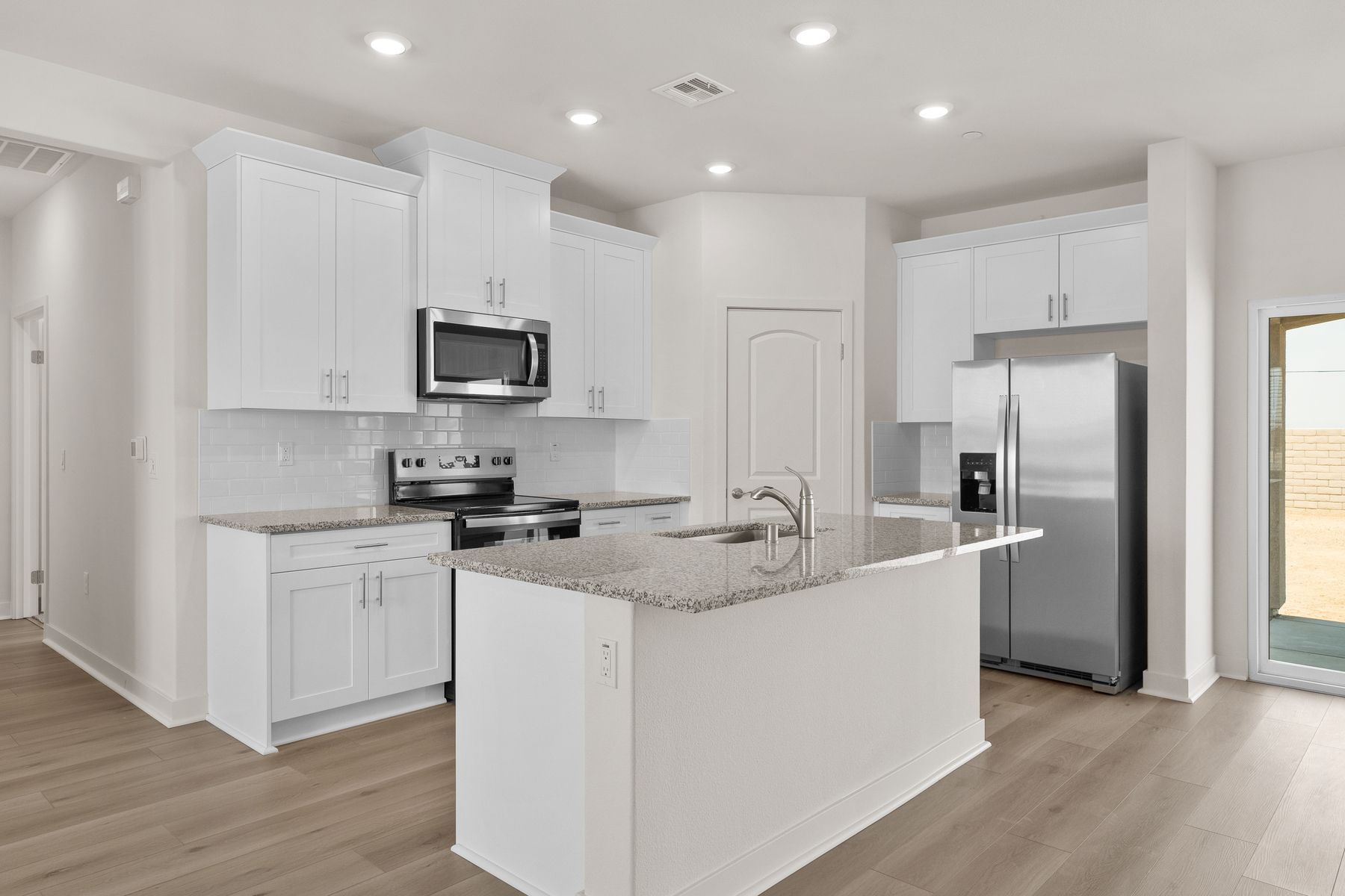 The kitchen has stainless steel appliances and plank flooring.