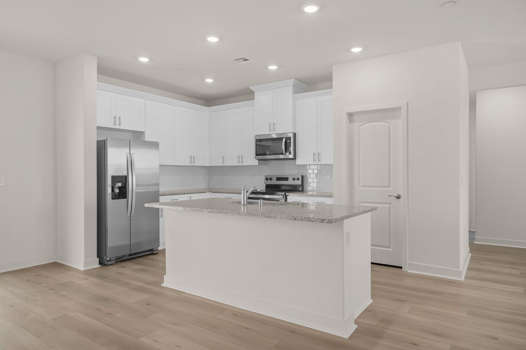 The kitchen has stainless steel appliances and plank flooring.