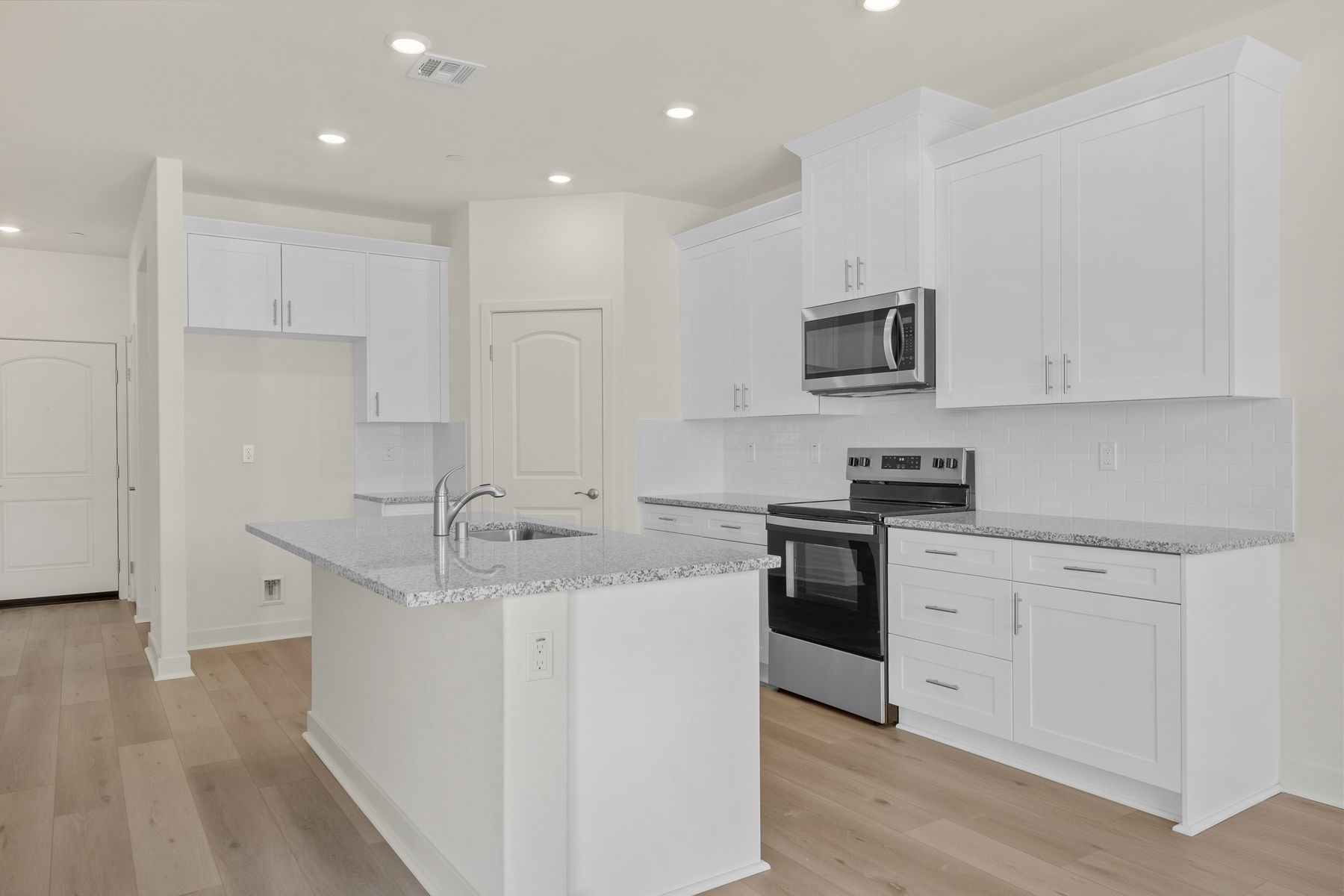 The kitchen has stainless steel appliances and plank flooring.