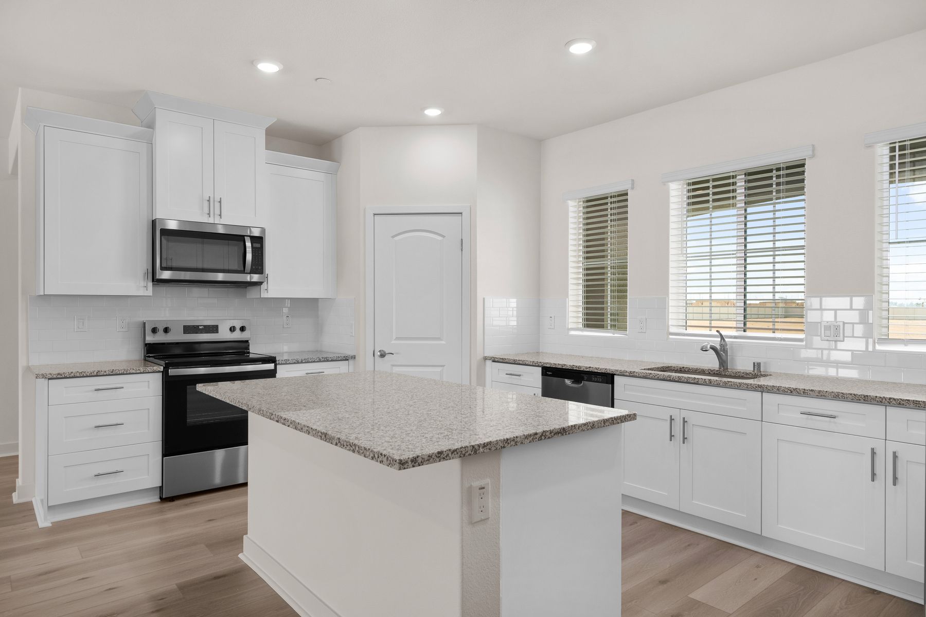 The kitchen has stainless steel appliances and plank flooring.