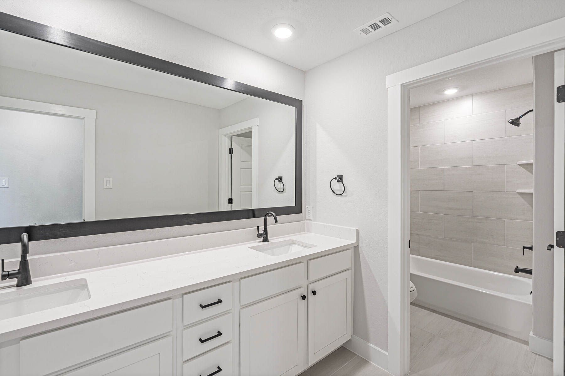 The secondary bathroom has a sprawling dual sink vanity and a shower-tub combo.