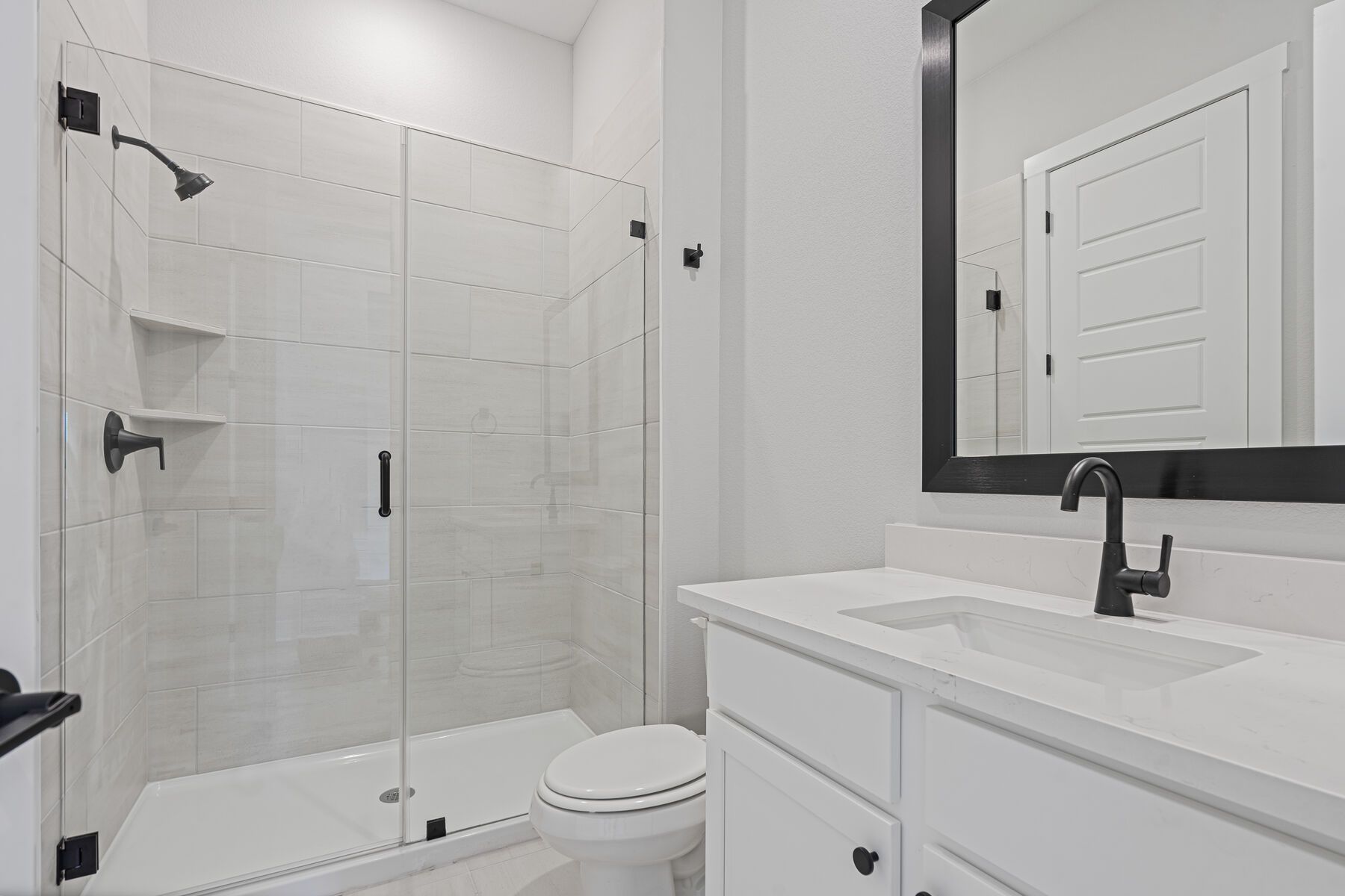The third bathroom has a sprawling vanity and glass, walk-in shower.