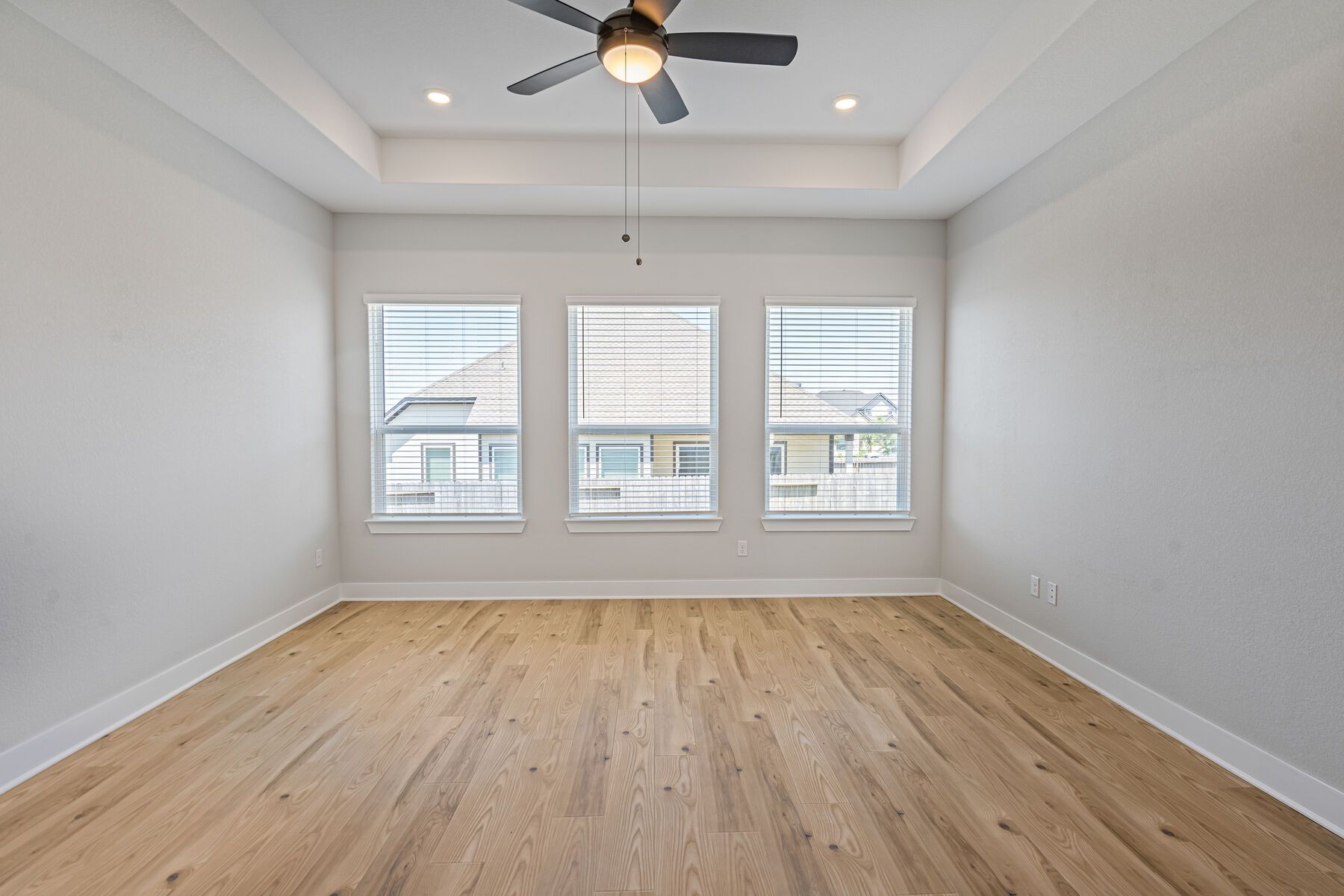 The master bedroom is spacious and has three large windows.