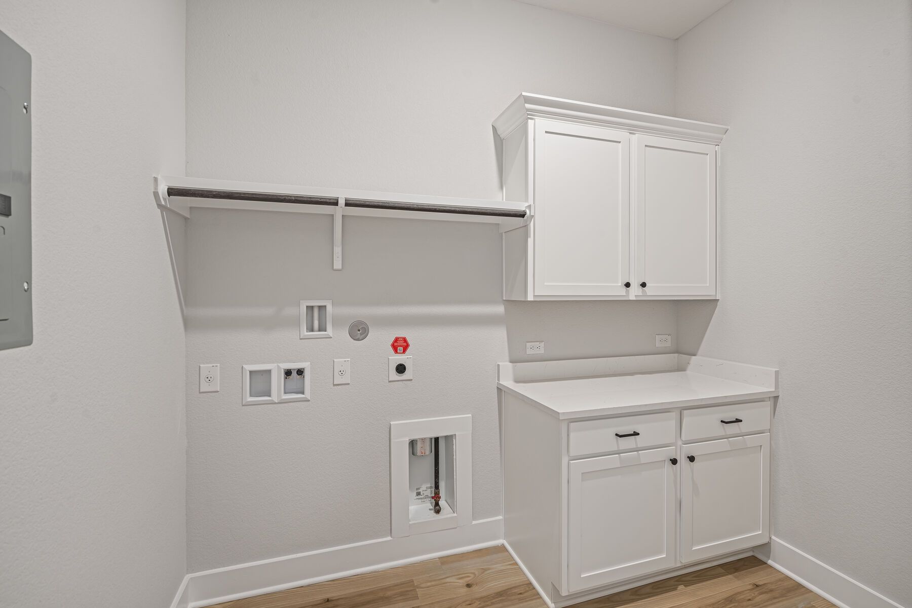 The laundry room has a hanging space and cabinets with a counter.