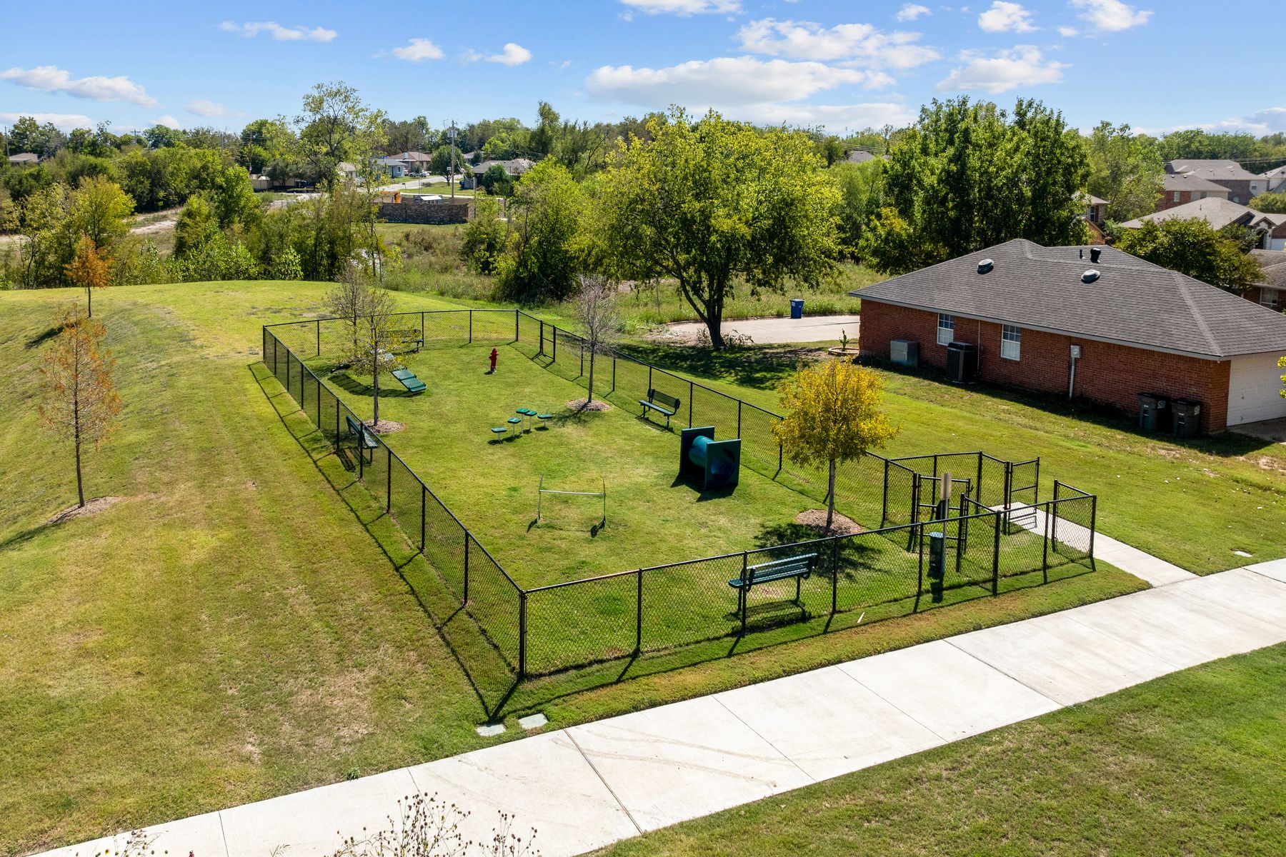 The wonderful dog park is fully fenced in and has plenty of grass and obstacles.