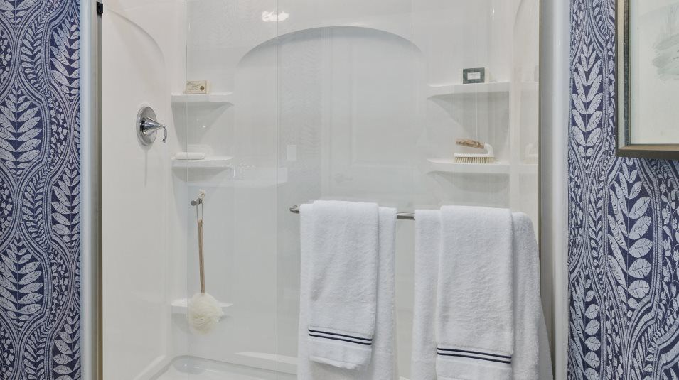 Fiberglass shower with framed glass enclosure and built in shelving