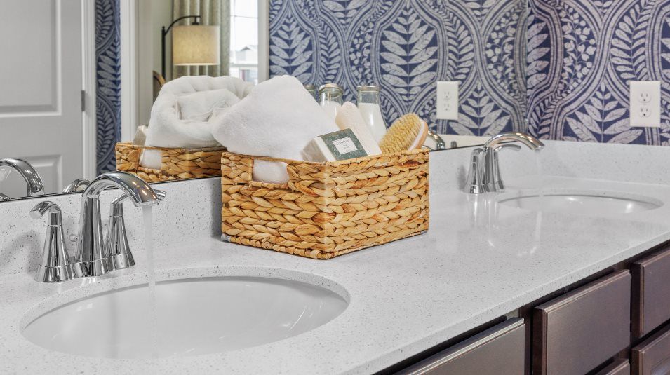 Dual undermount sinks atop a vanity with quartz countertops and Moen® double lever faucets in the ow