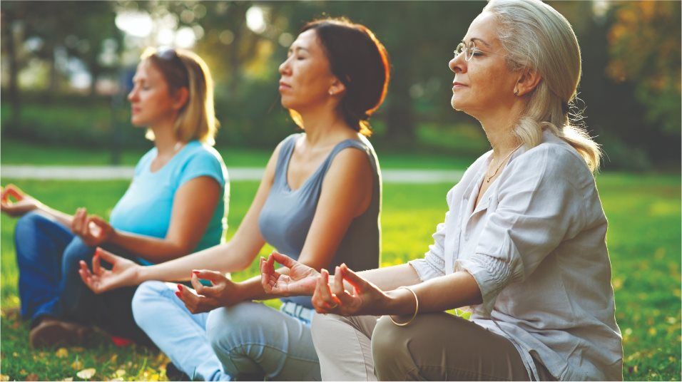 Three women practicing yoga outdoors