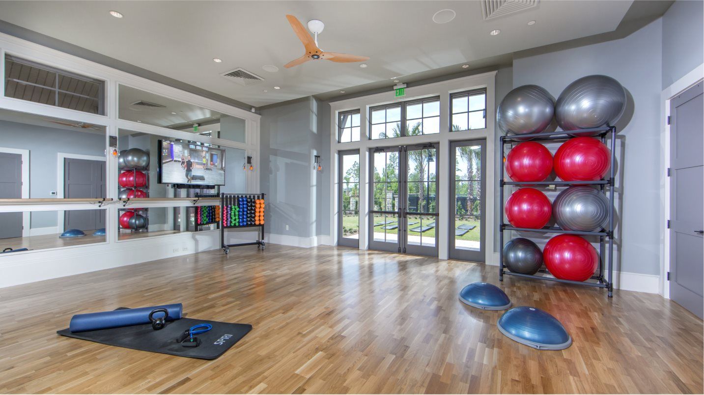Aerobics room with an instructor on TV teaching a yoga class, small dumbbells and exercise balls