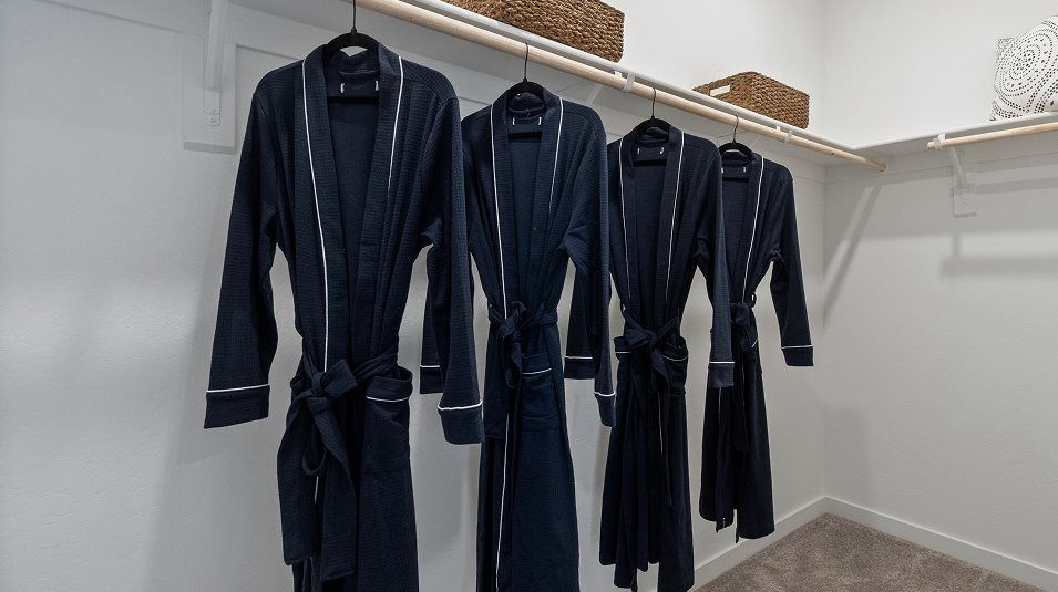 Wood shelving and rods for wardrobe organization in the owner’s suite walk-in closet