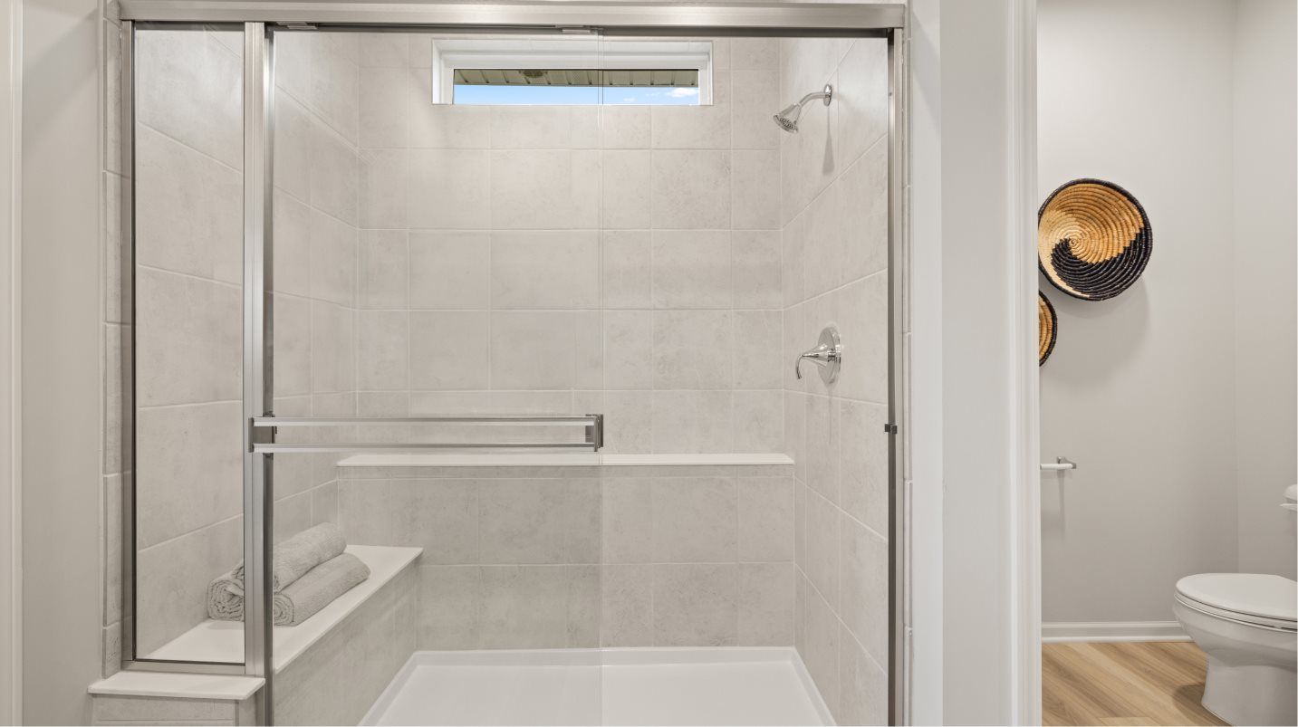 Owners suite shower includes a built-in seat and ceramic tile walls