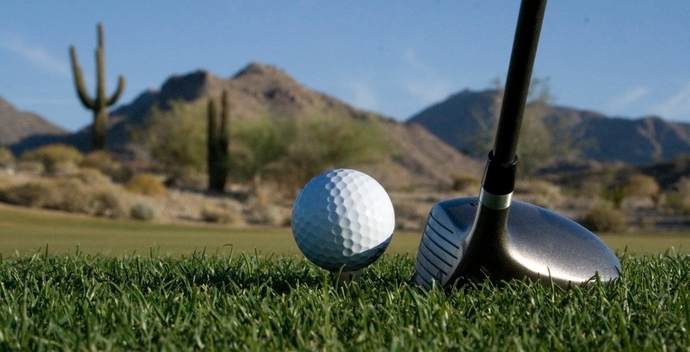 Close up of a golf ball and putter on a desert lawn