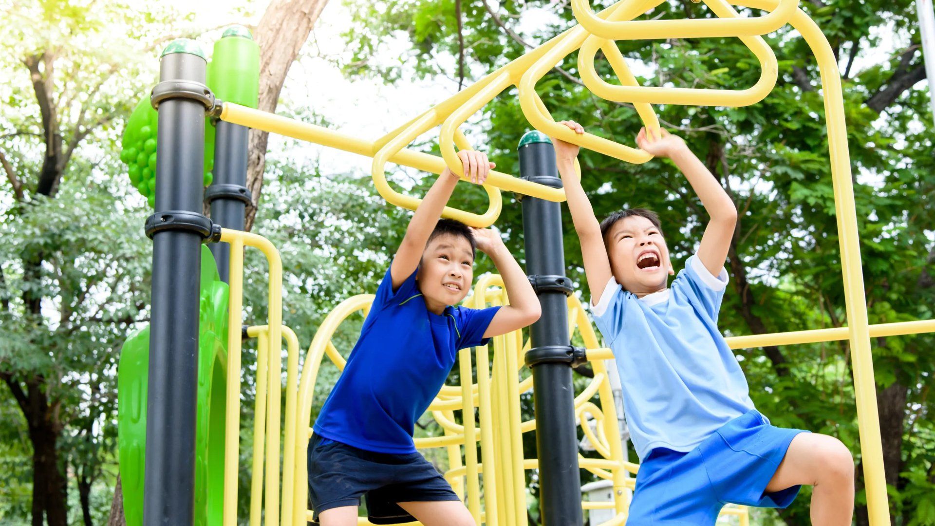 Two boys swinging on monkey bars