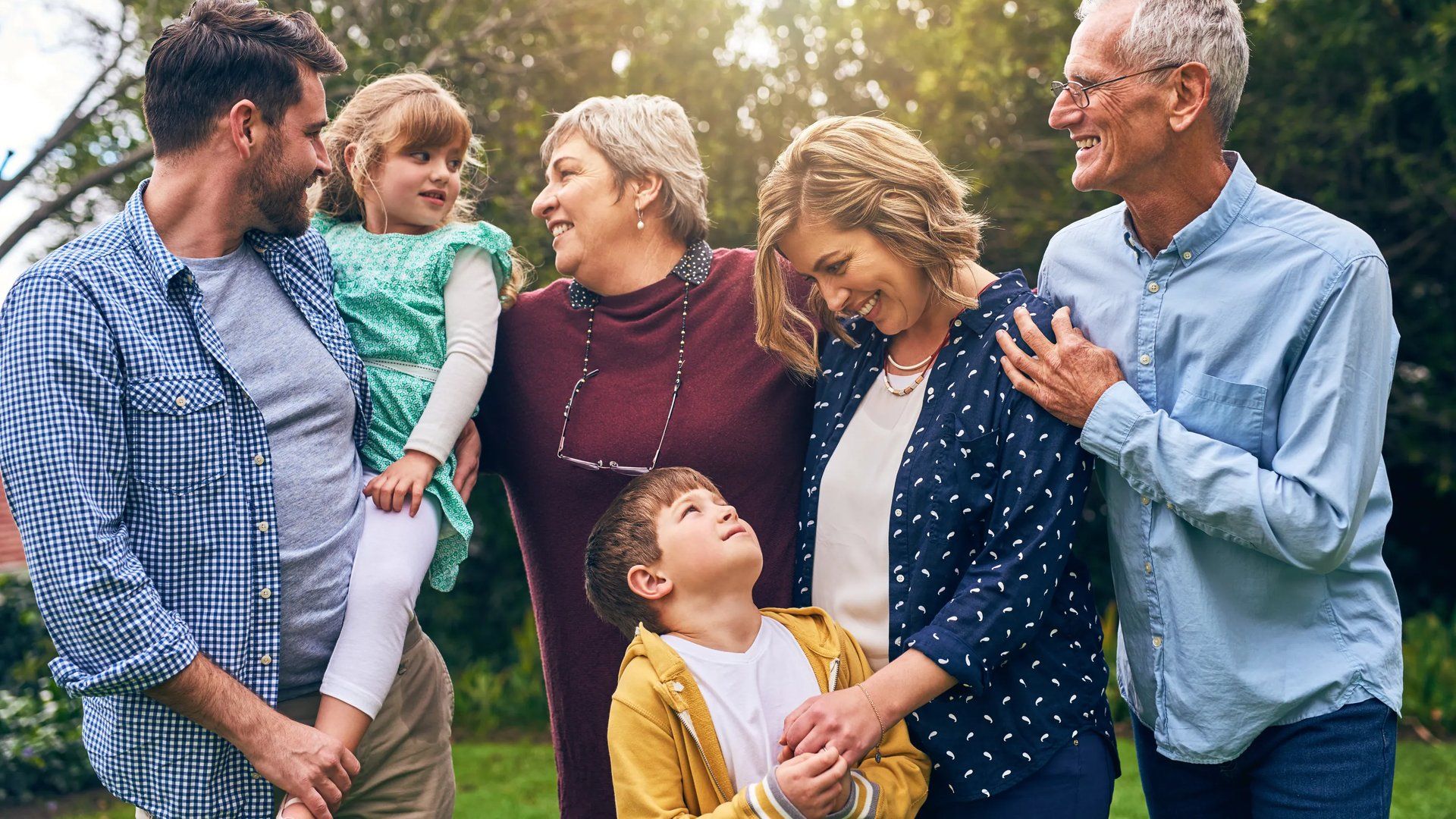 Multigenerational family standing outdoors looking at each other