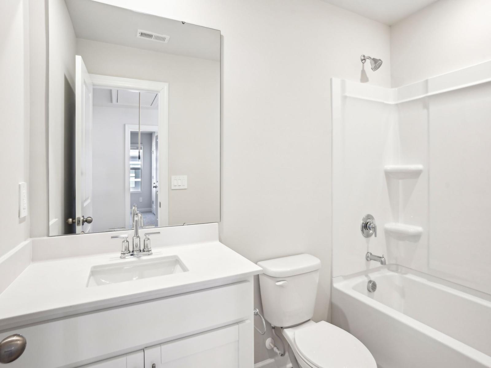 The secondary bathroom featuring a large mirror and oversized tub.
