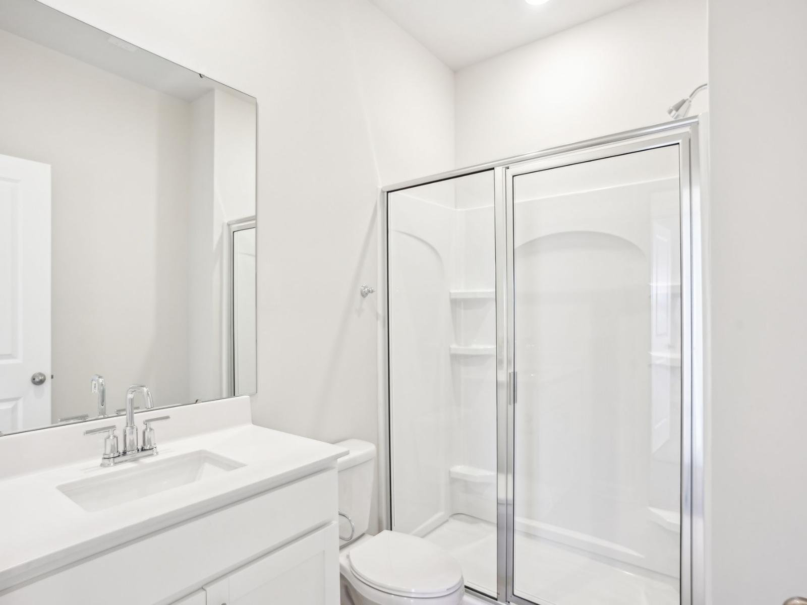 A secondary bathroom with a glass walk-in shower and modern vanity.