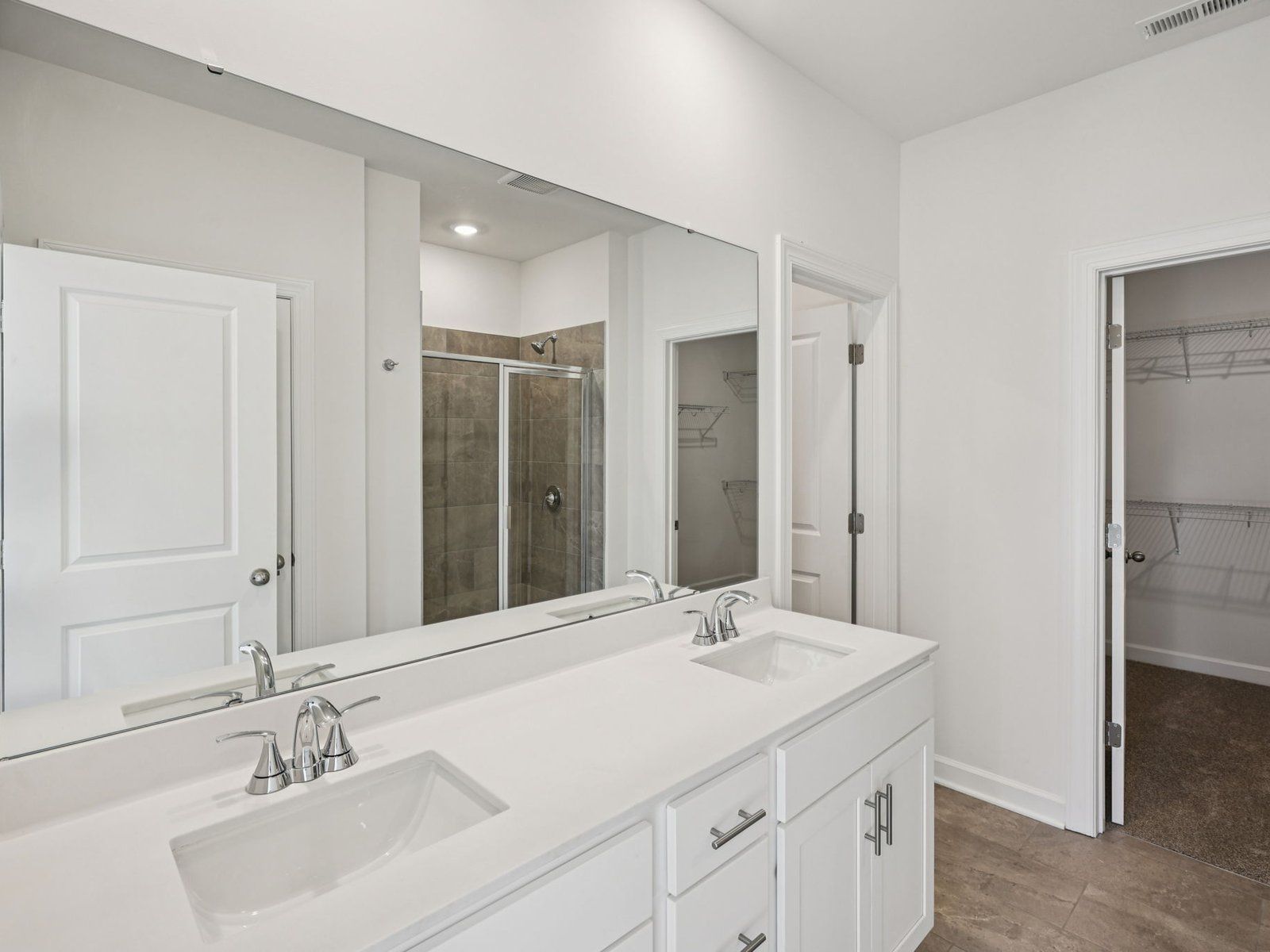 The primary bathroom boasts a dual-sink vanity and modern walk-in shower.