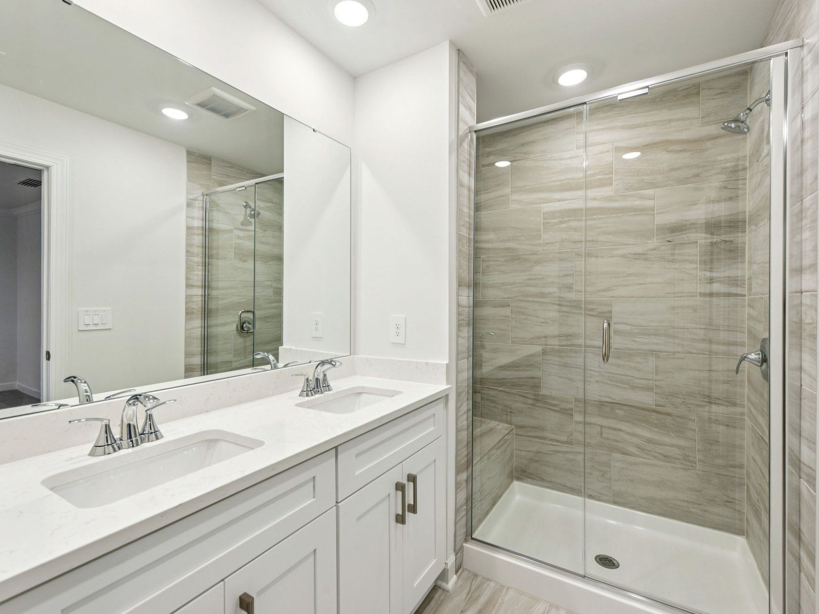 The primary bathroom boasts a dual-sink vanity and modern walk-in shower.