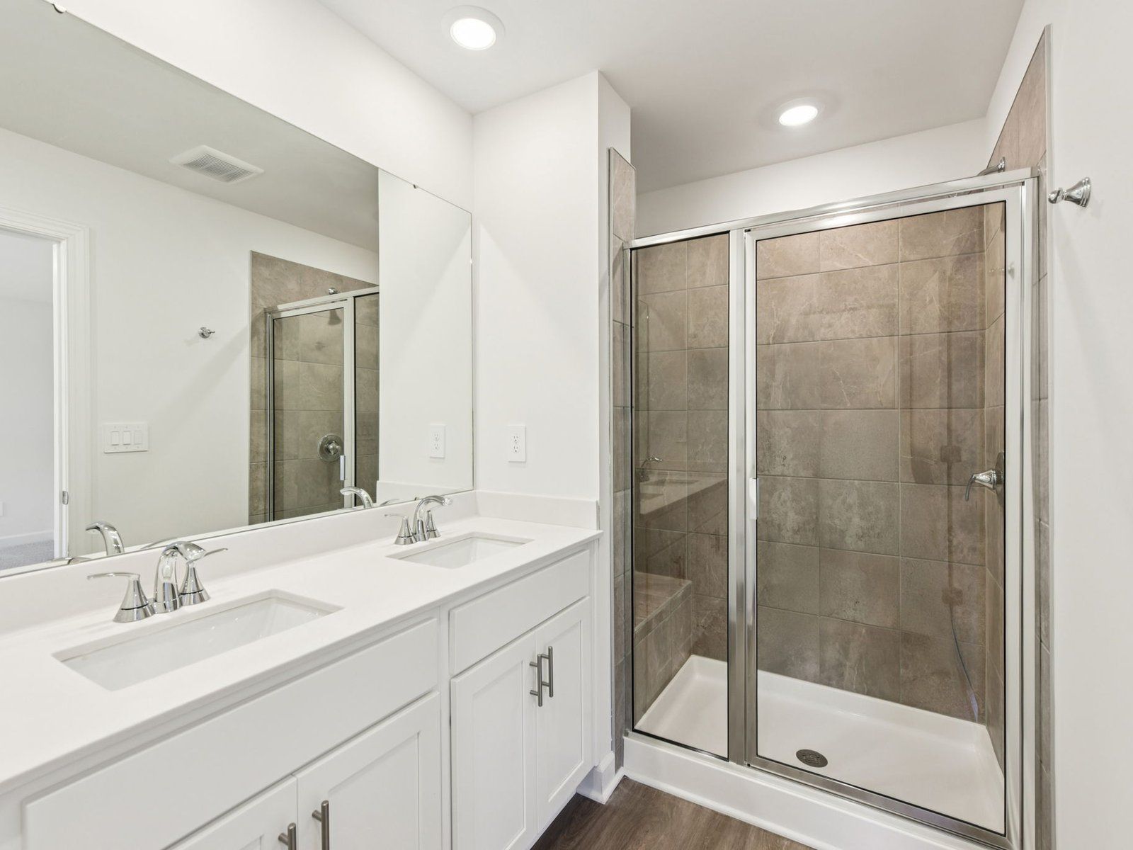 The primary bathroom boasts a dual-sink storage vanity and modern walk-in shower.