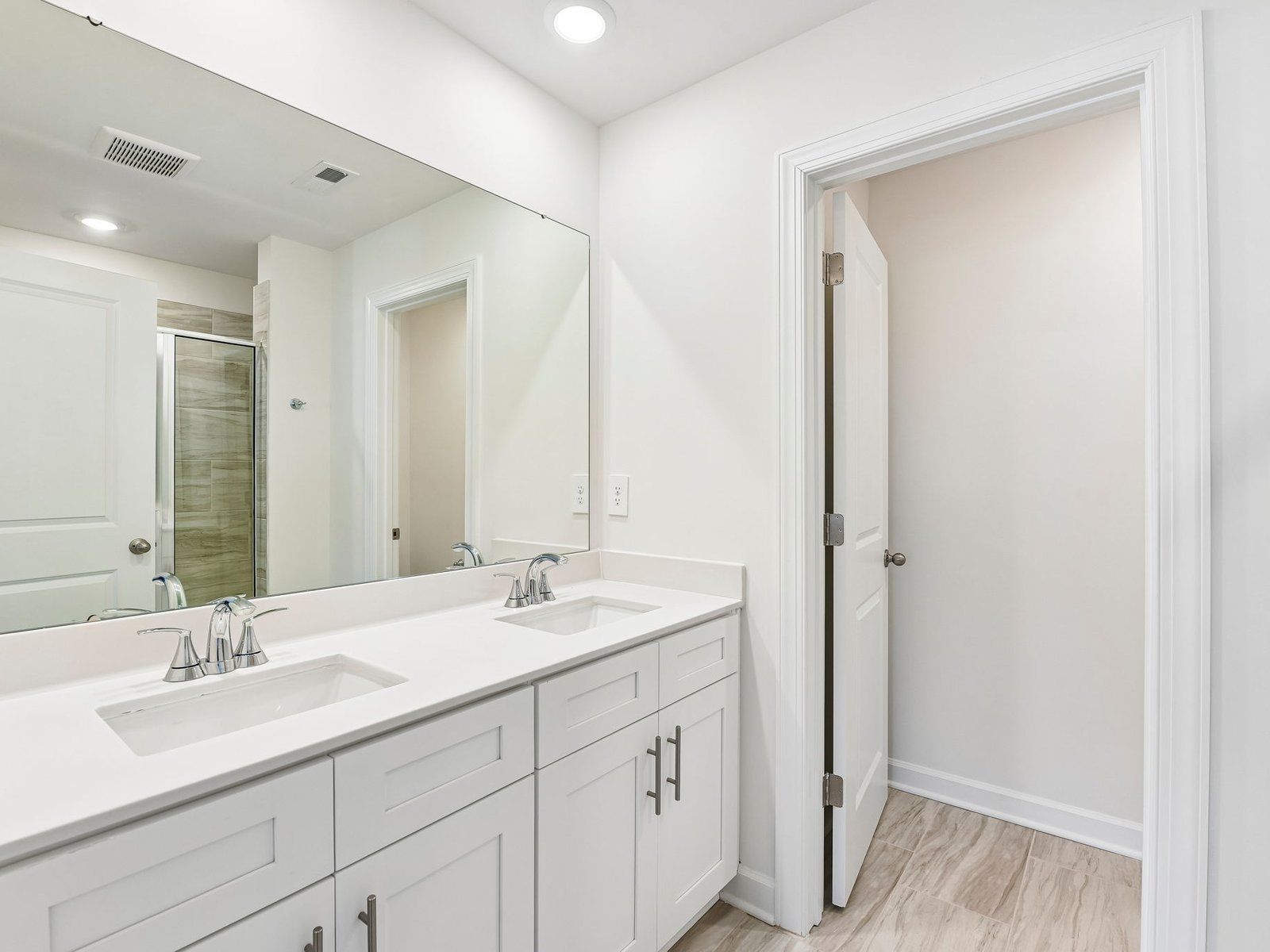 The primary bathroom boasts a dual-sink vanity and modern walk-in shower.