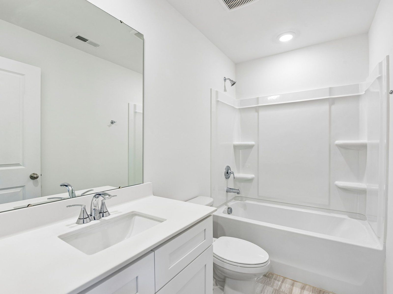 The secondary bathroom features a storage vanity and an oversized shower tub.