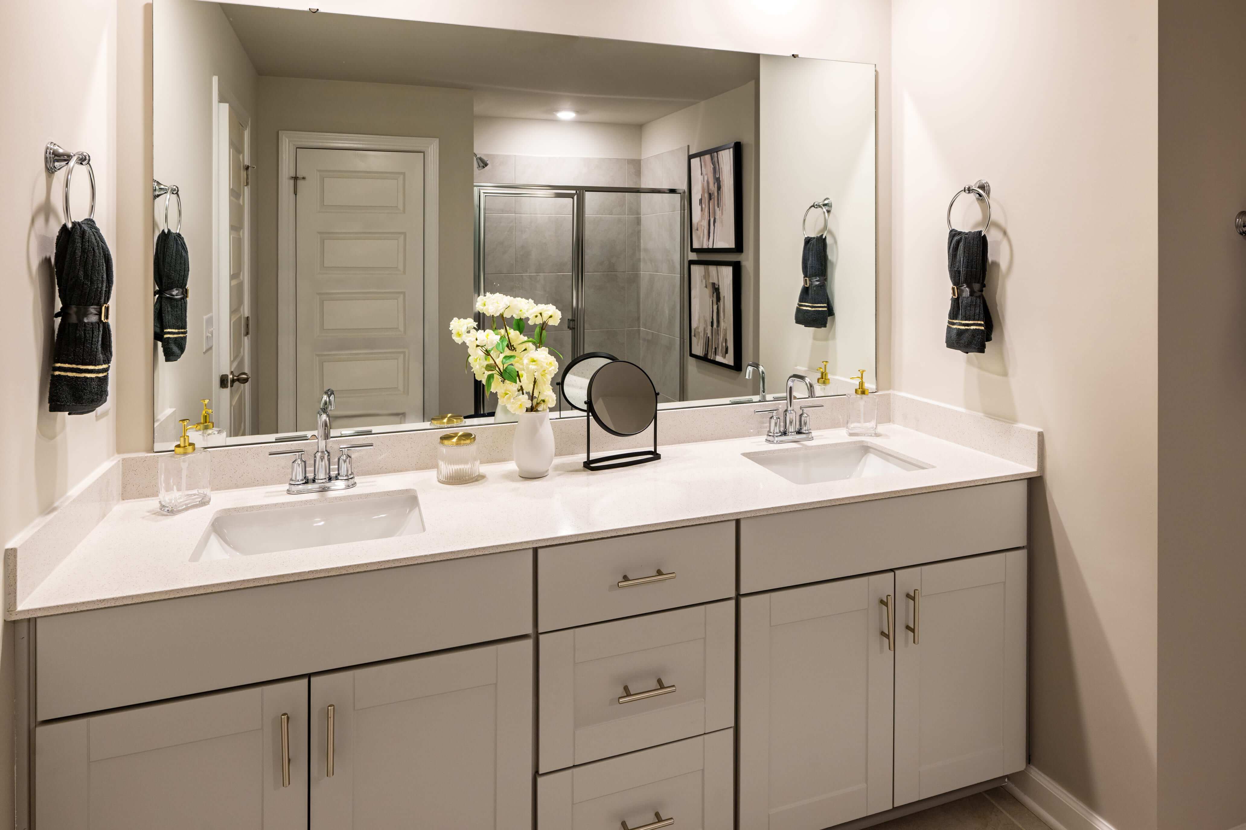 The primary bath offers dual vanity sinks and a walk-in shower. Photography from Holland Park.
