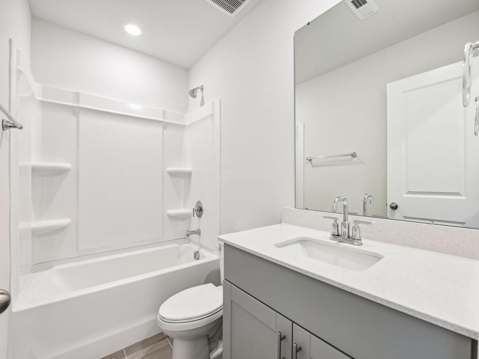 The secondary bathroom with a large tub and spacious cabinets.