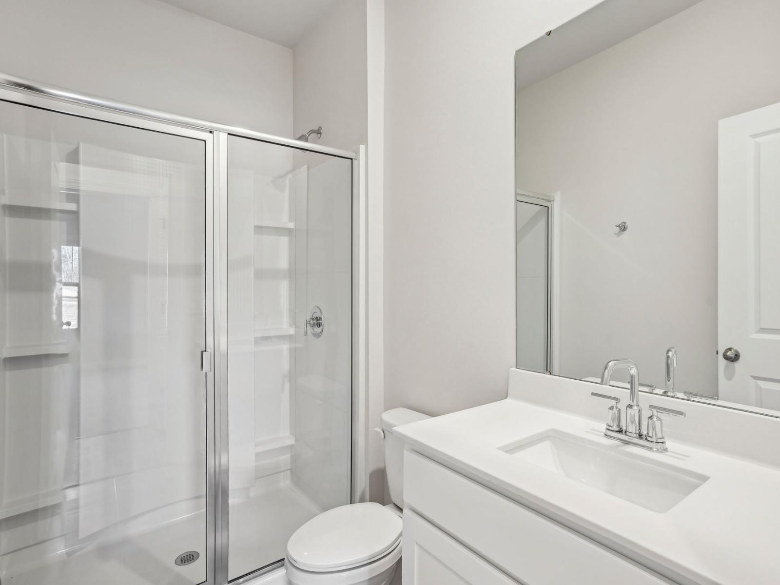 A secondary bathroom with a walk-in shower and large mirror.