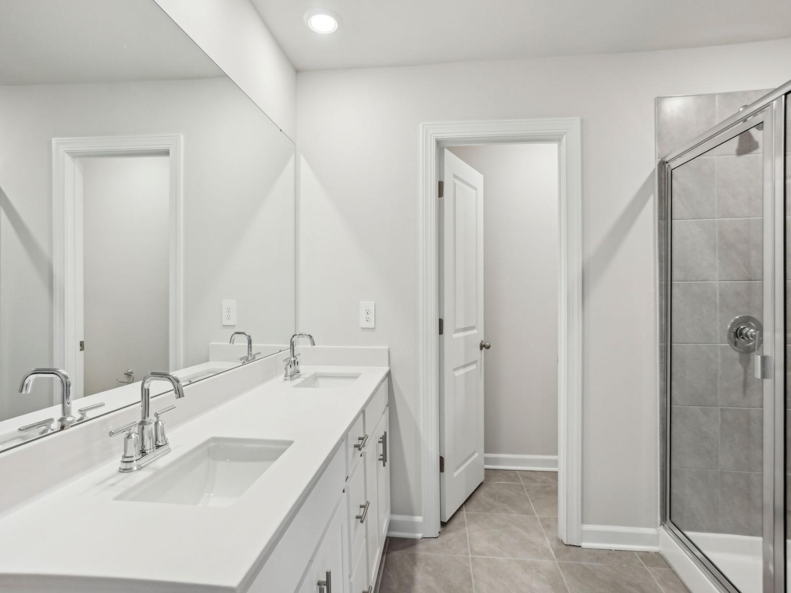 The primary bathroom featuring a walk-in closet and double-sink vanity.