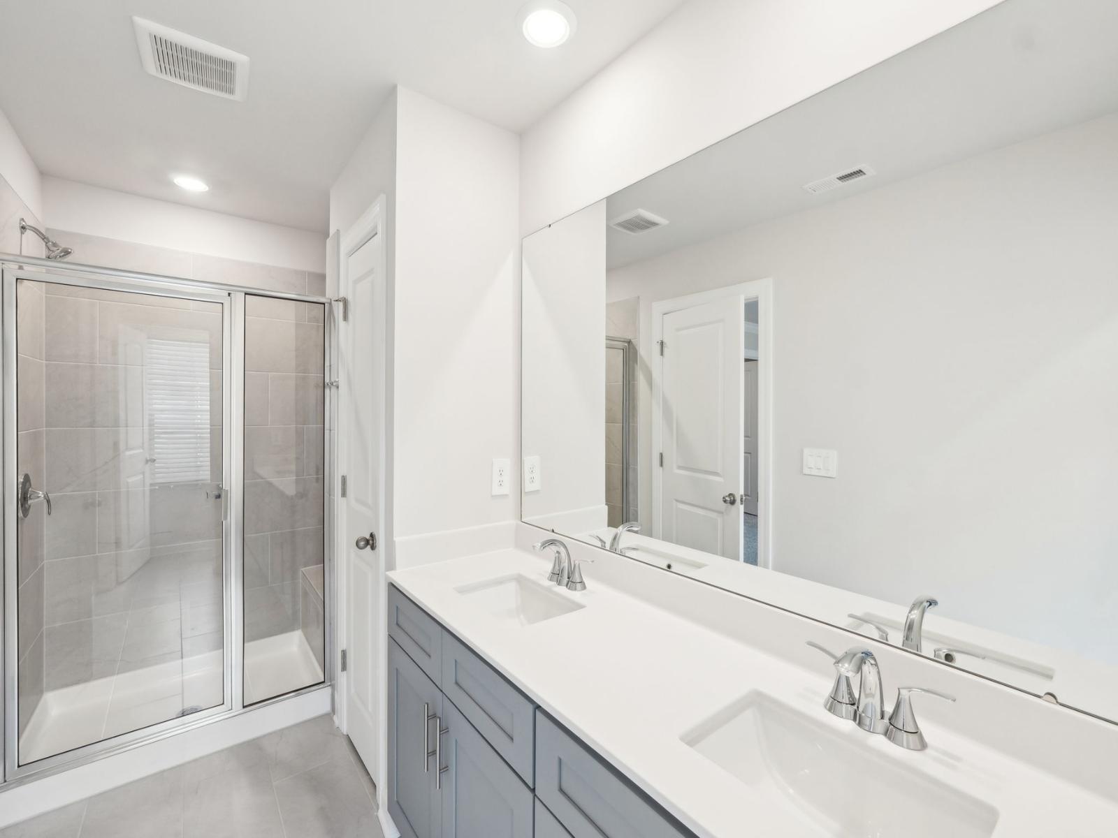 The primary bathroom features an oversized mirror and walk-in shower.