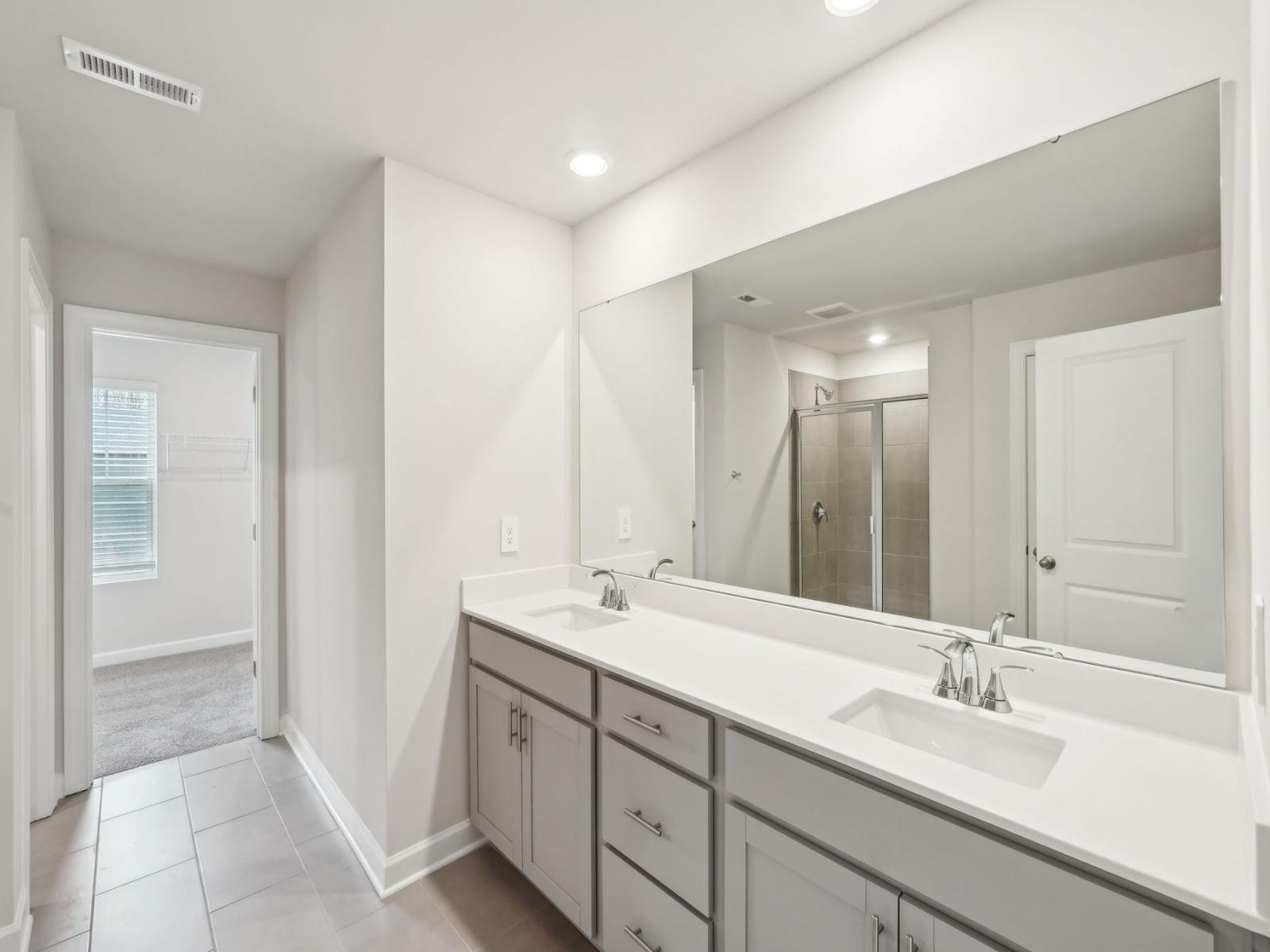 Enjoy spa day in the primary bathroom with a walk-in shower and double-sink vanity.