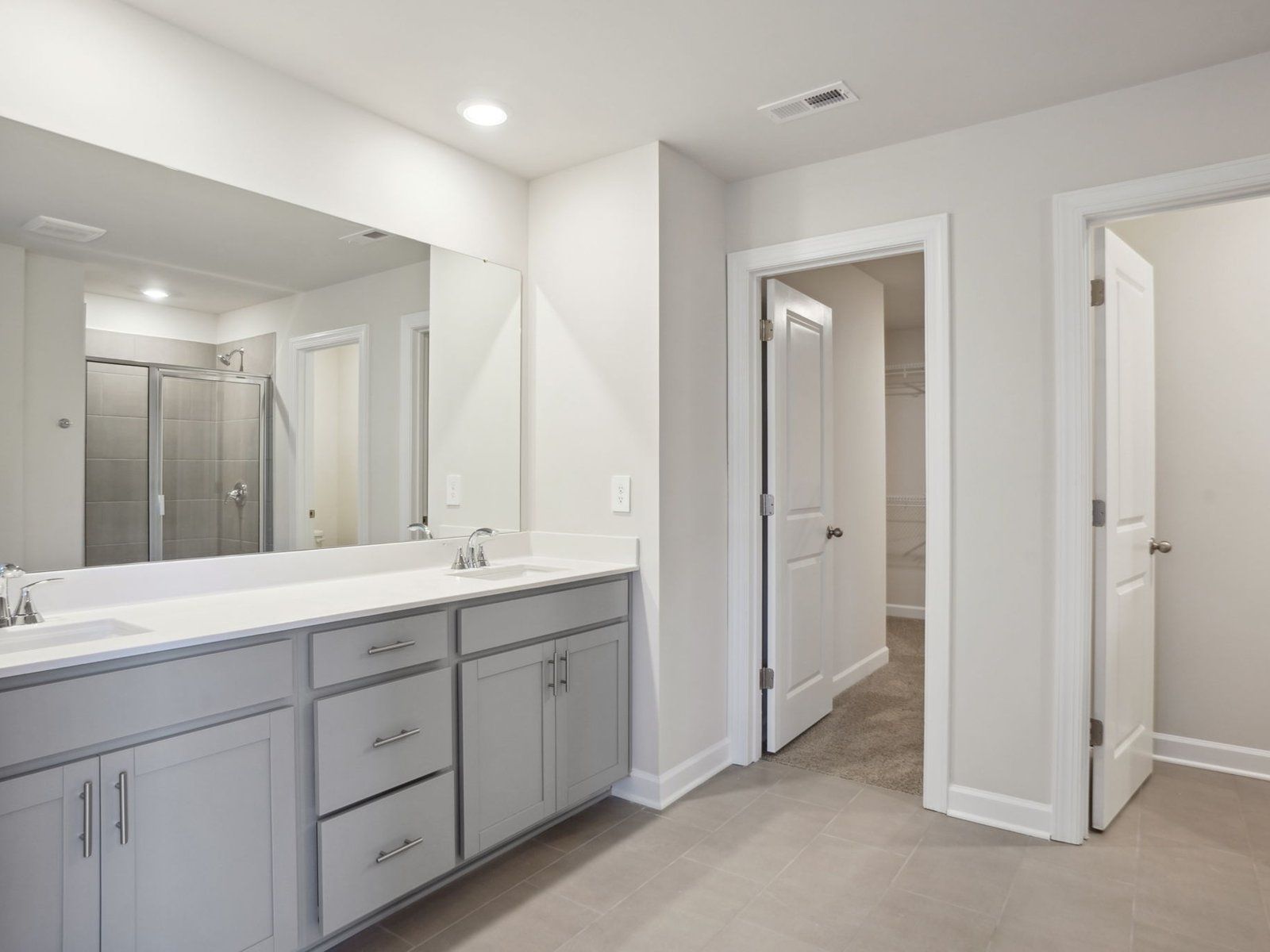 The primary bathroom features dual-sinks and a spacious walk-in shower.