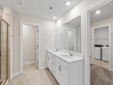 The modern primary bathroom offers a spa-like experience with convenient access to the laundry room.