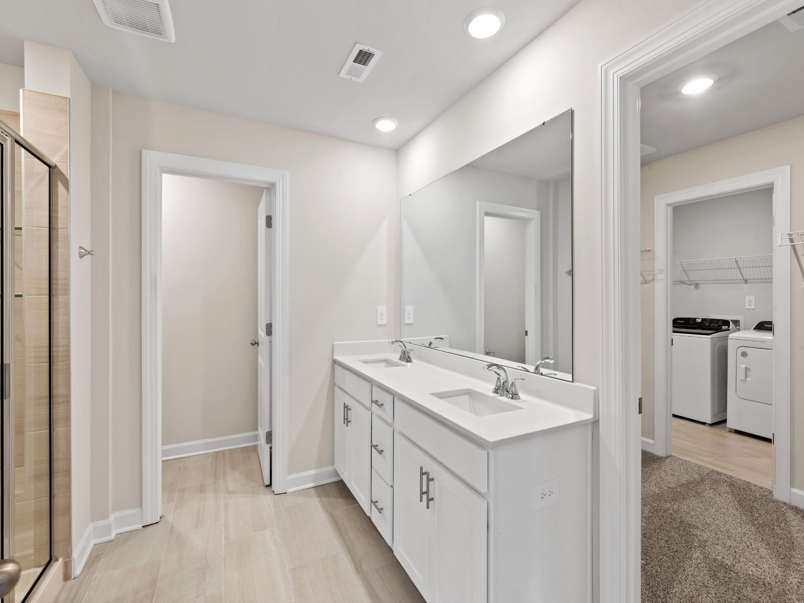 The modern primary bathroom offers a spa-like experience with convenient access to the laundry room.