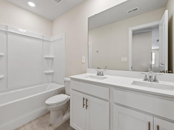The secondary bathroom boasts a dual-sink vanity and oversized shower tub.