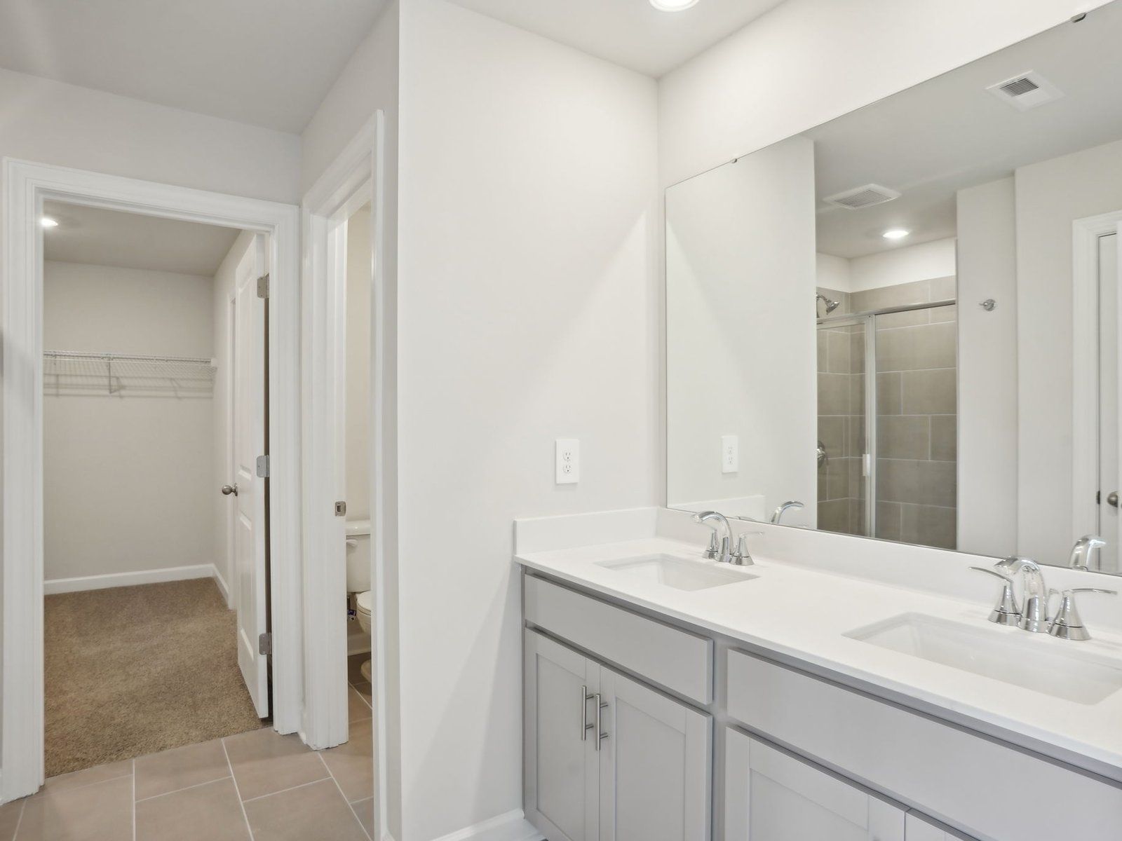 The primary bathroom boasts a dual-sink vanity and spacious walk-in shower.