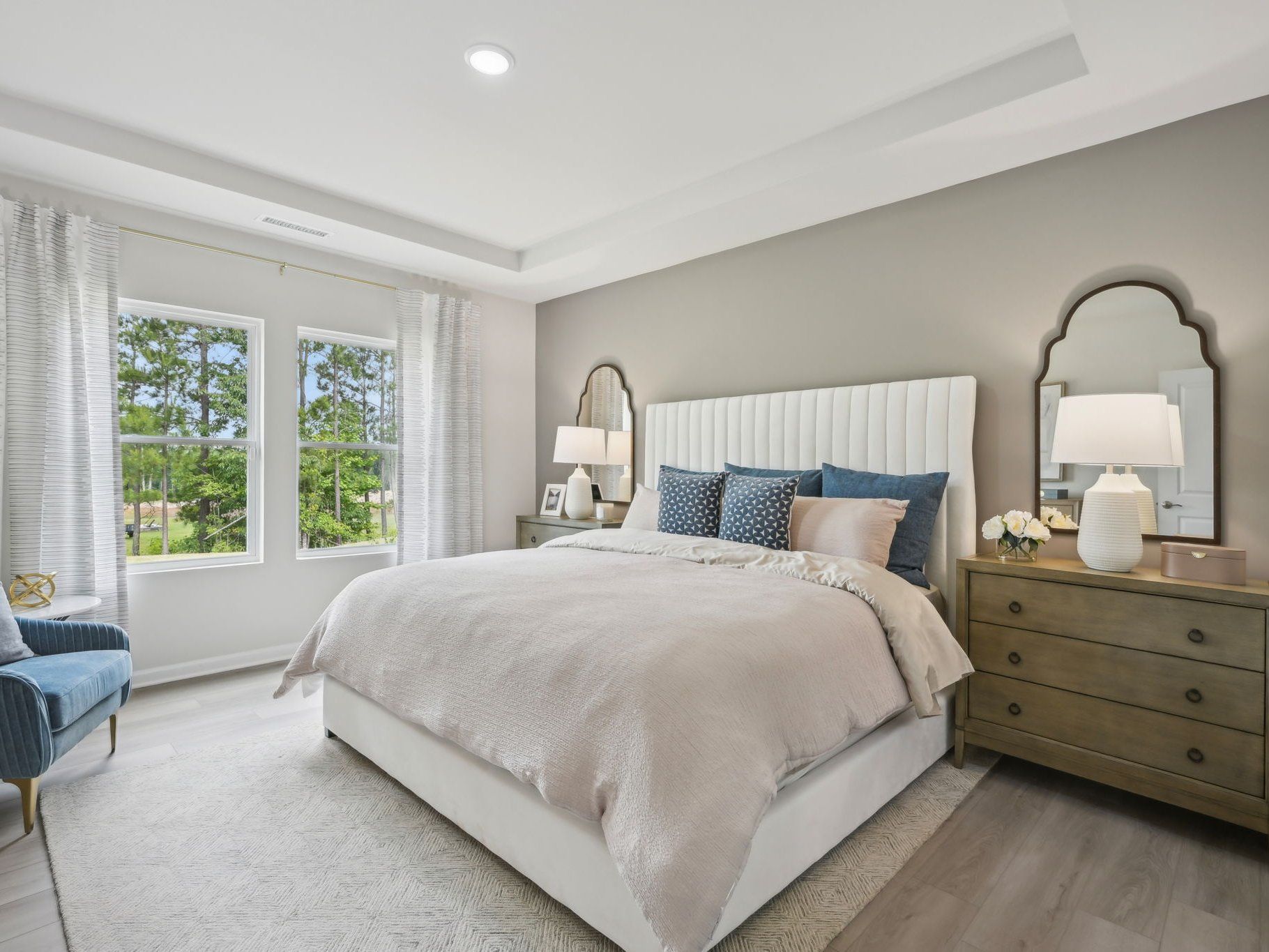 The luxurious primary suite featuring a tray ceiling, dual sinks and a spacious closet.