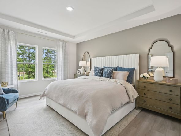 The luxurious primary suite featuring a tray ceiling, dual sinks and a spacious closet.