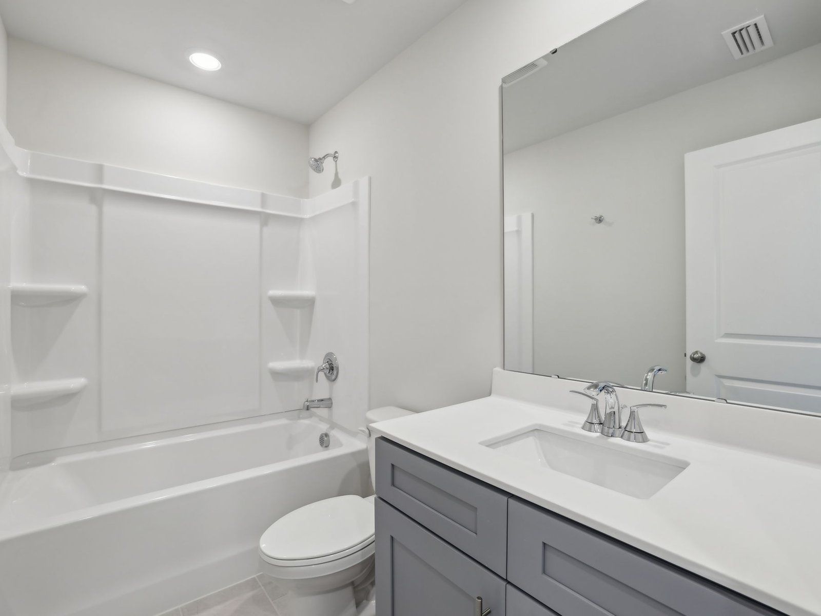 The secondary bathroom features a spacious vanity and oversized shower tub.