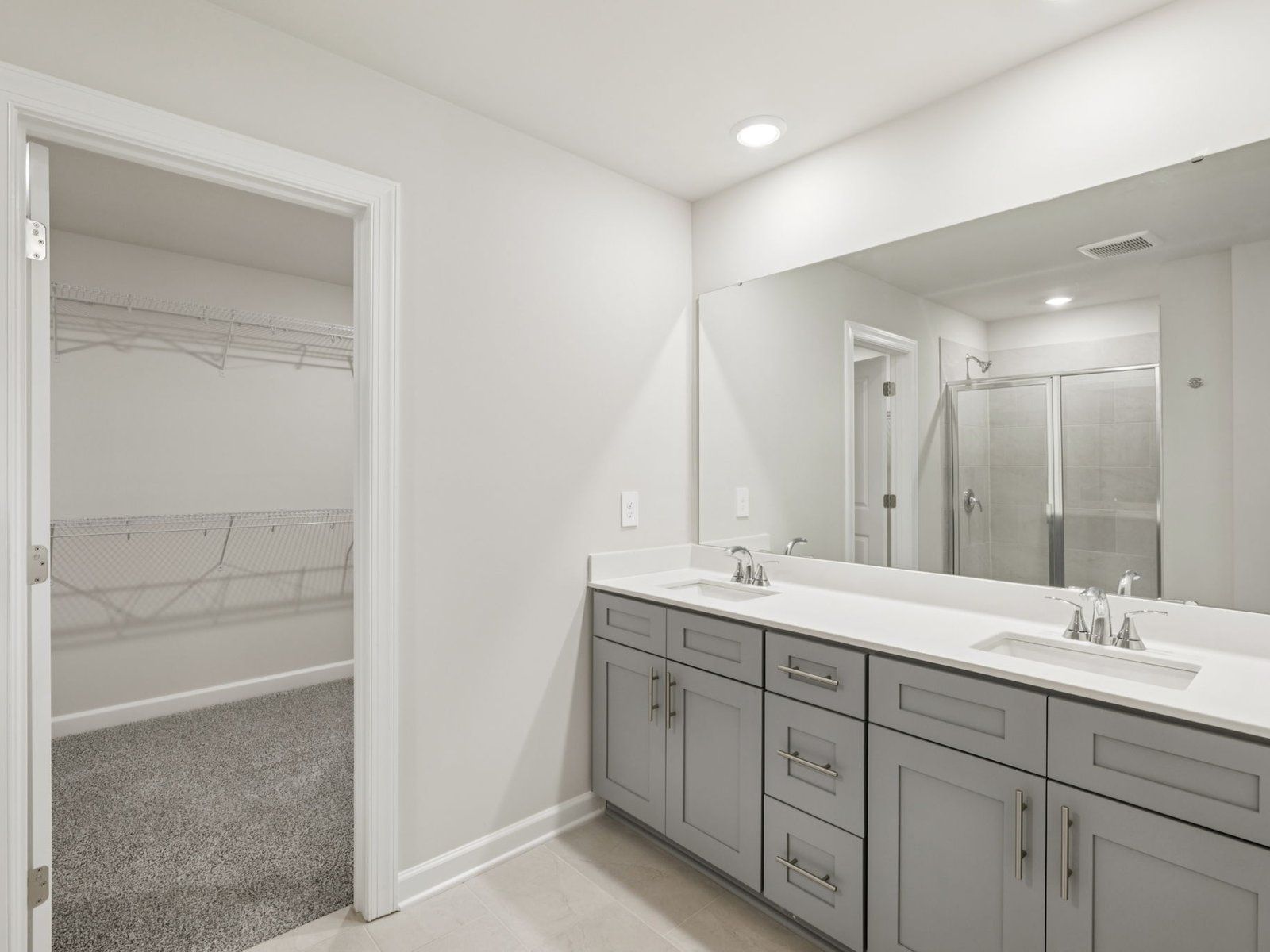 The primary bathroom boasts dual sinks and a spacious walk-in shower.