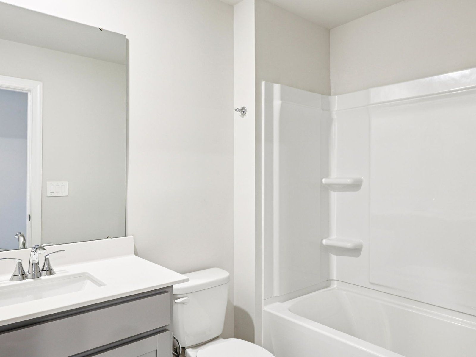 The secondary bathroom features a spacious vanity and oversized shower tub.