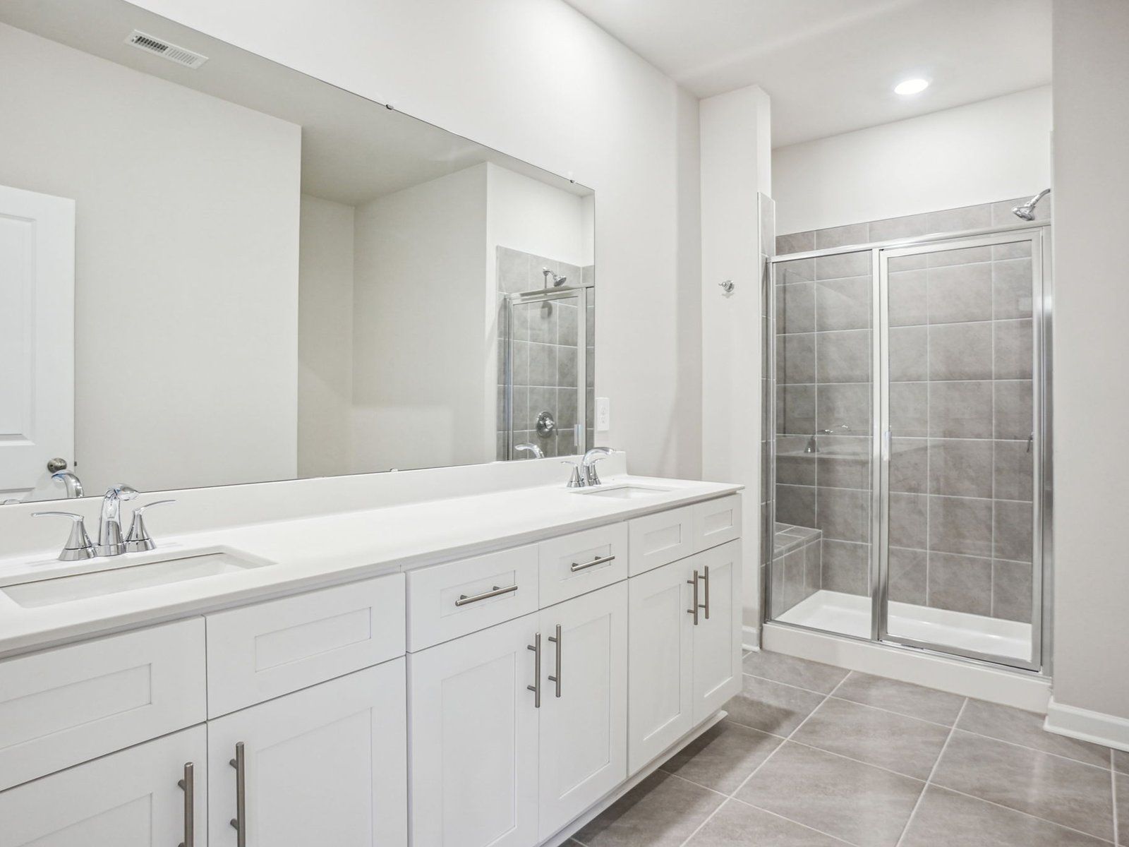 The primary bathroom features a spa-like walk-in shower and large dual-sinks.