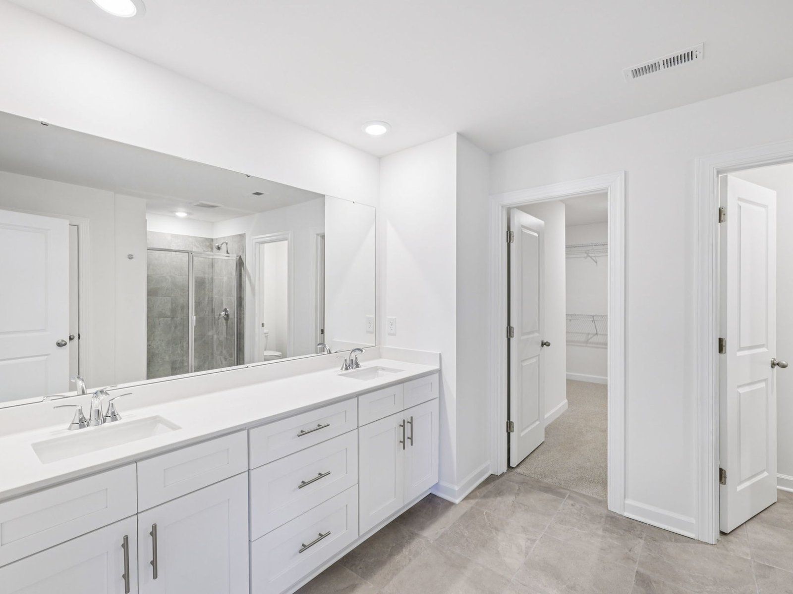 The primary bathroom boasts a dual-sink vanity and modern walk-in shower.