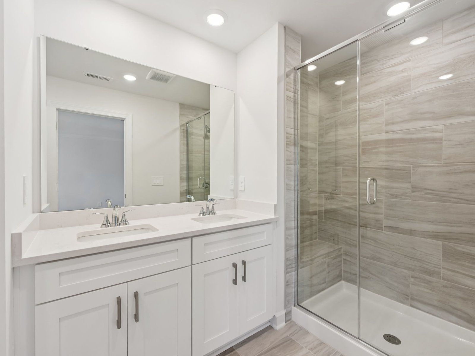 The primary bathroom boasts a dual-sink vanity and modern walk-in shower.