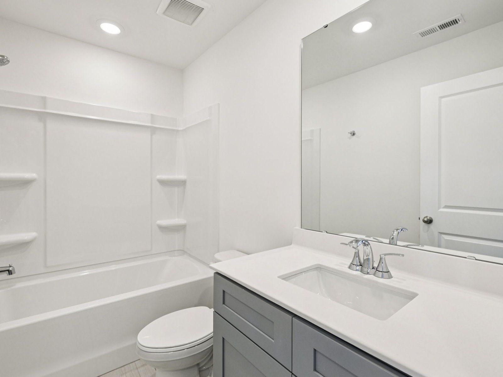 The secondary bathroom features a storage vanity and an oversized shower tub.