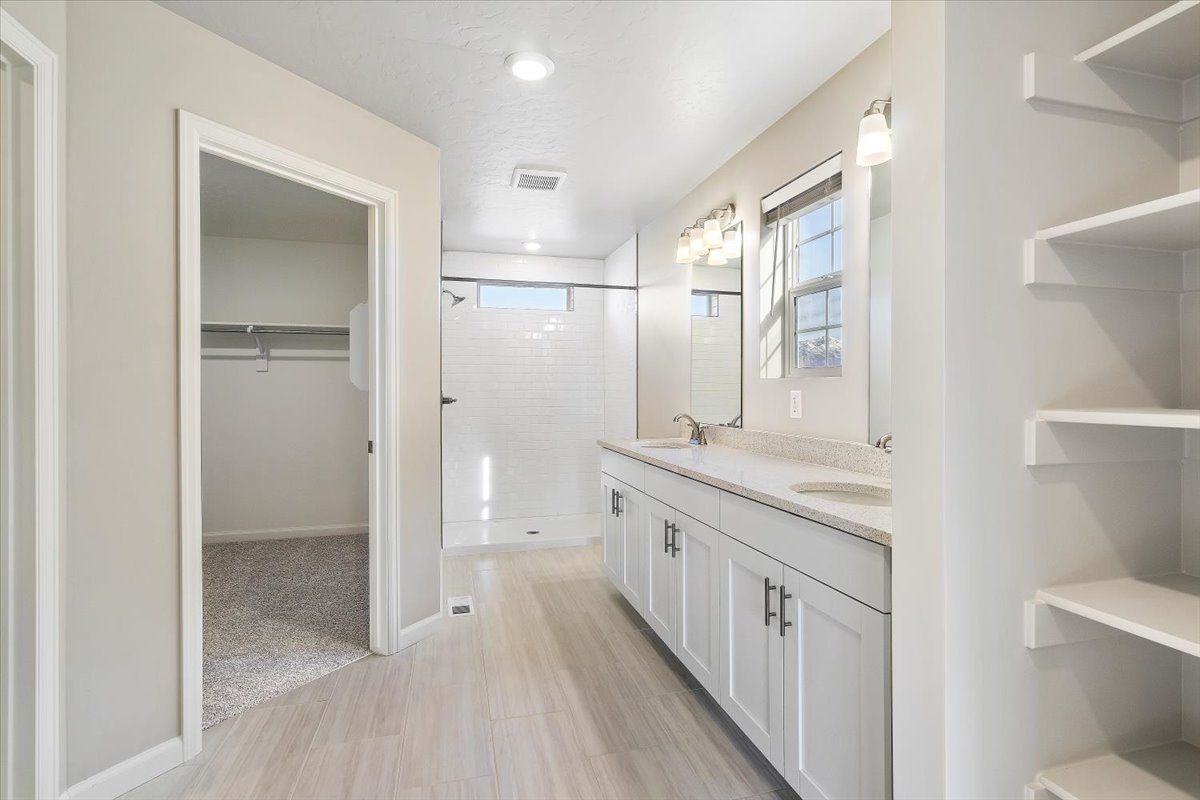 A view of the primary bathroom, walk in shower, walk in closet and vanity