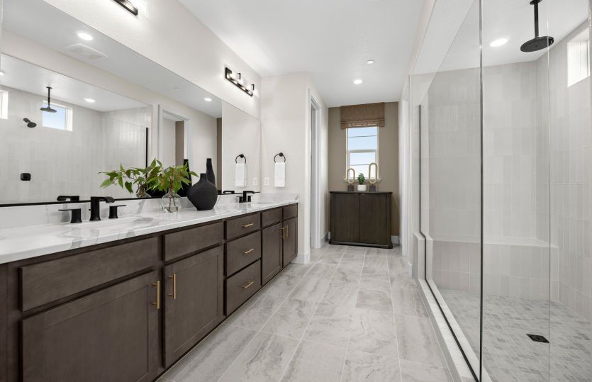 Spacious primary bathroom with glass walk-in shower and dual vanities