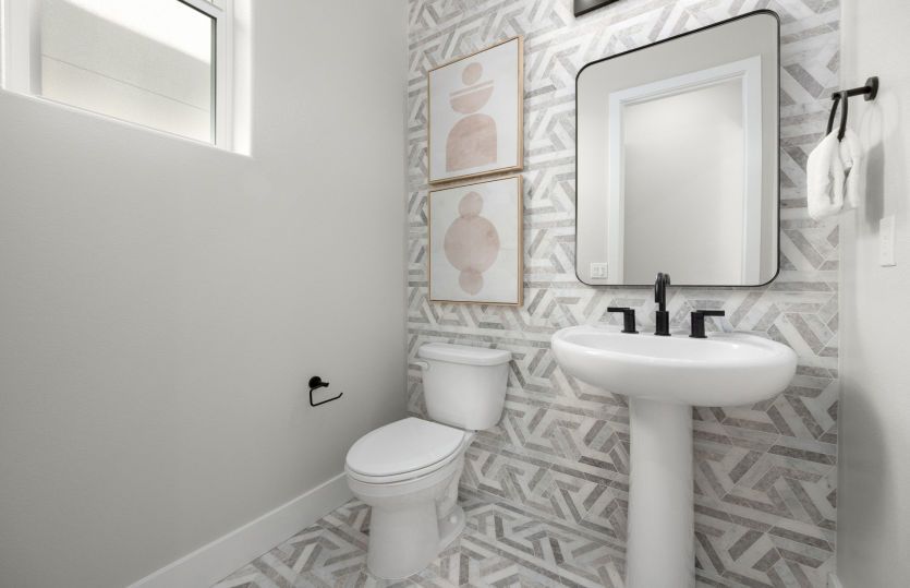 Half bath with framed mirror and tiled wall