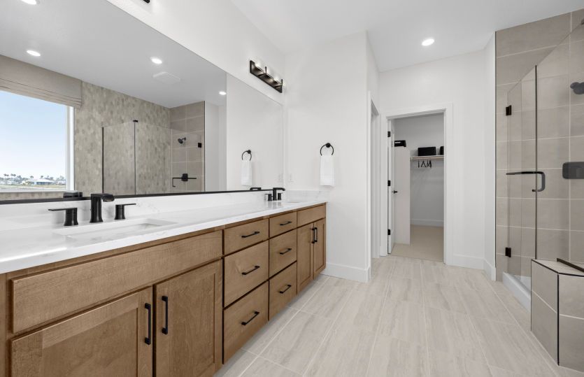Owner's bathroom with dual vanities and a glass walk-in shower